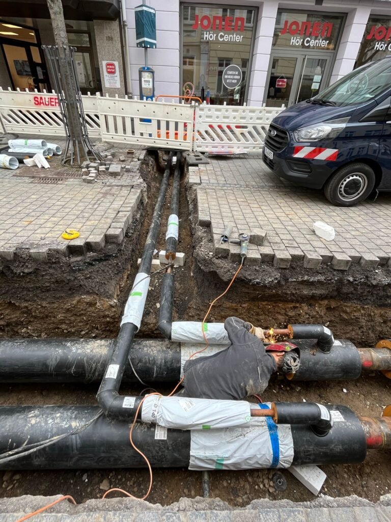 Fernwärme-Rohranschlüsse in einem Straßengraben