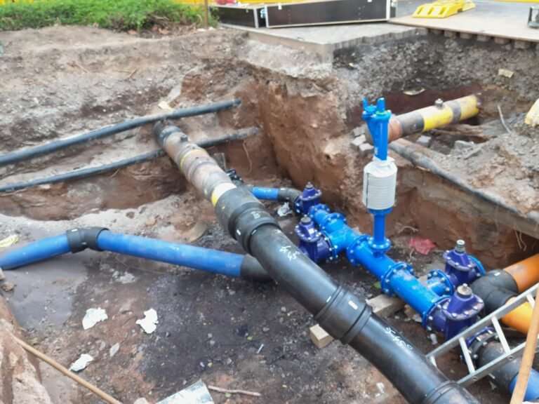 Blaue Wasserleitung mit Armatur in einer Baugrube