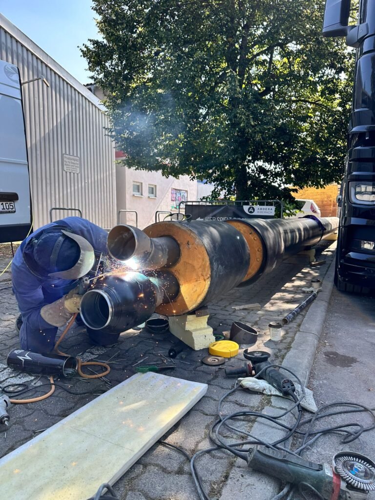 Schweißer verbindet vorisolierte Rohre auf der Baustelle
