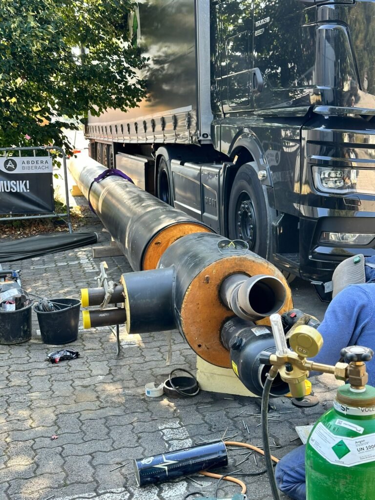 Schweißausrüstung und vorisolierte Rohre neben einem LKW