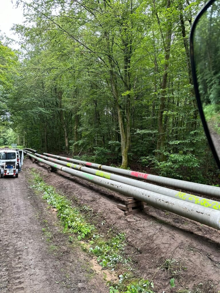 Vorisolierte Rohre entlang eines Waldwegs ausgelegt