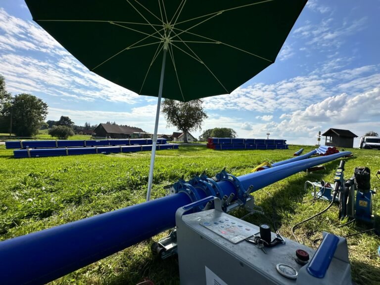 PE-Stumpfschweißmaschine an einer blauen PE-Leitung auf einem Feld