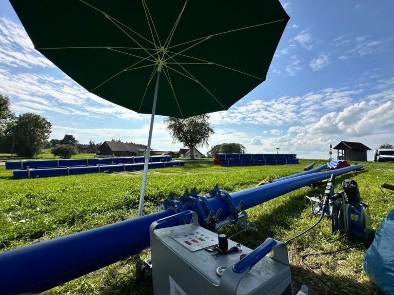 PE-Stumpfschweißmaschine an einer blauen PE-Leitung auf einem Feld