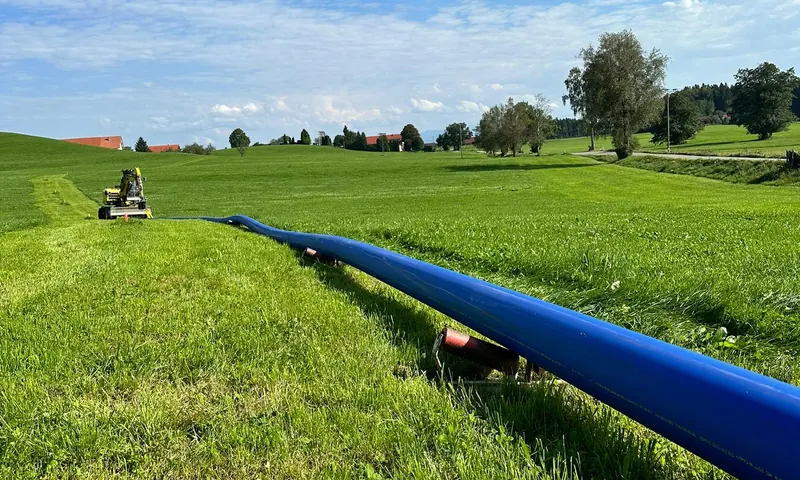 Blaue PE-Leitung über eine Wiese verlegt